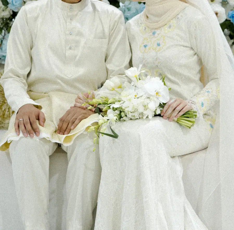 Izzah on the pelamin with her white orchid bouquet